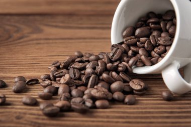 Beyaz bardakta kahve çekirdekleri dokulu ahşap masa