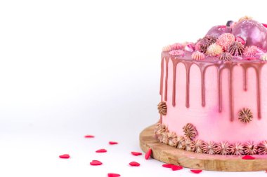 Doğum günü pastasında pembe krema ve krema serpiştirilmiş, kalp şeklinde simler ve tatlılar serpiştirilmiş. Beyaz arka planda ev yapımı kek..