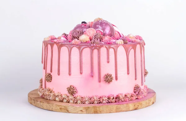 Bolo de aniversário com creme rosa e cobertura, polvilhado com glitter e doces na forma de corações. Bolo caseiro em um fundo branco. — Fotografia de Stock