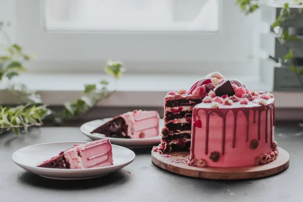 Cut chocolate cake dengan krim pink dan glaze ditaburi dengan permen. Sepotong kue di piring. — Stok Foto