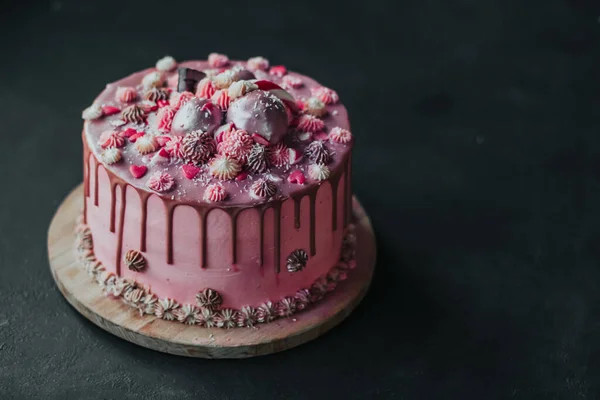 Narozeninový dort s růžovou smetanou a čokoládovou polevou, posypaný srdíčky a sladkostmi. Domácí dort kopie prostor — Stock fotografie