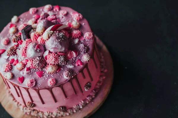 Kue ulang tahun dengan krim merah muda dan gula-gula coklat, ditaburi dengan hati dan permen. Ruang penyalinan kue buatan sendiri — Stok Foto