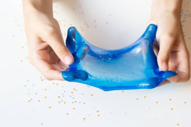 Çocuk elleri beyaz arka planda mavi sümük yapar. Yakın plan..