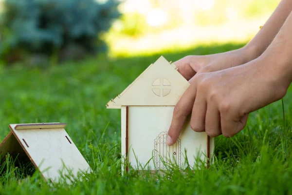 子供たちは緑の芝生の上の木造の家のモックアップを収集します 手を閉じる 家族の価値観 自分の手で建てられた家 テキストの場所 — ストック写真