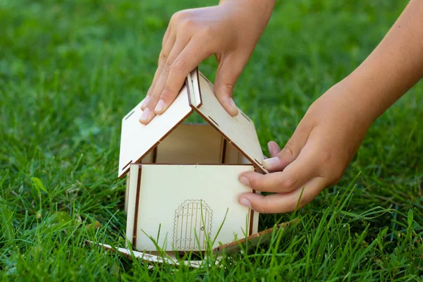 Dítě Sbírá Zelené Trávě Model Dřevěného Domu Detailní Záběr Rukou — Stock fotografie