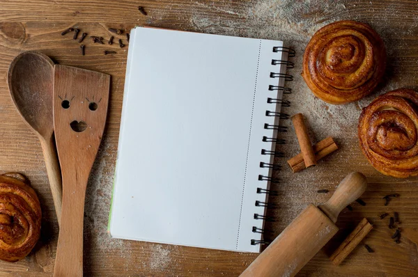 Open receptenboek met houten lepel, glooiende pan en spatel — Stockfoto