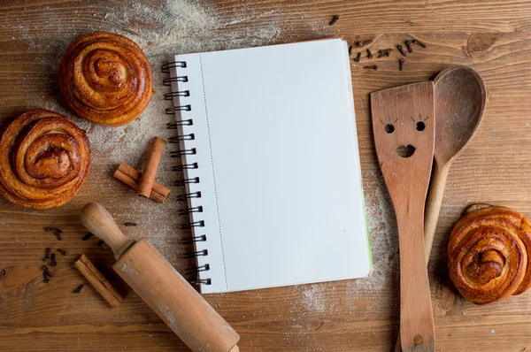 Libro di ricette aperto con cucchiaio di legno, padella e spatola — Foto Stock