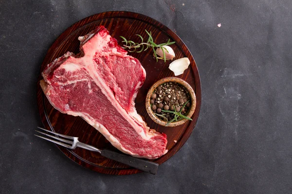 Thick raw T-bone steak with seasoning — Stock Photo, Image