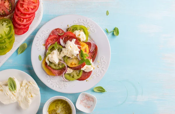 Tomates coloridos, queijo, pesto e salada no prato — Fotografia de Stock