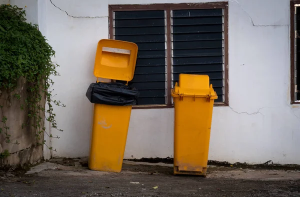 Two yellow trash bins on the wall