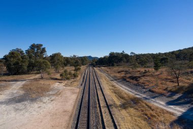 Avustralya 'daki açık mavi gökyüzünün altında taşraya giden tren yolları.