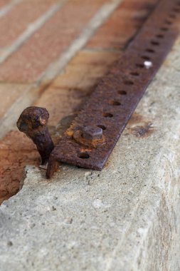 Kırık beton üzerine eski paslı cıvata ve metal açılı demir parçası.