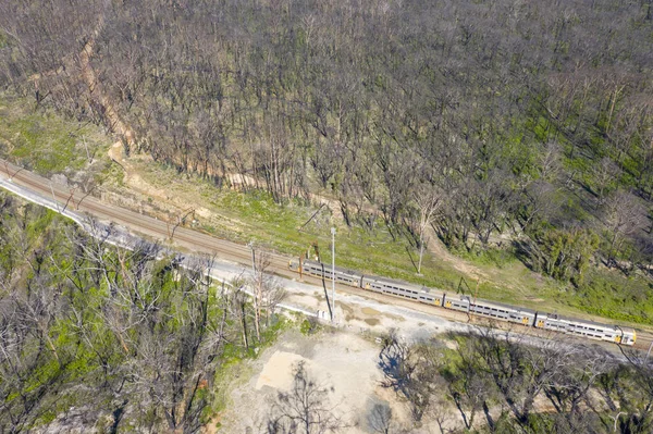 Aerial view of a train running through and area of forest regeneration after bushfire in Dargan in the Central Tablelands in regional New South Wales Australia