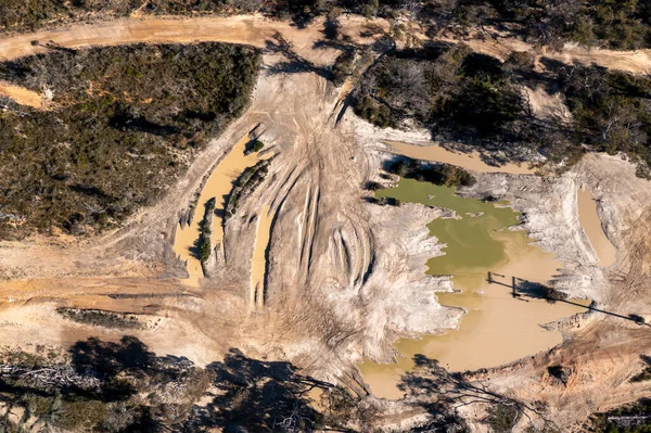 Drone aerial photograph of flood water on a dirt road in a forest in regional Australia