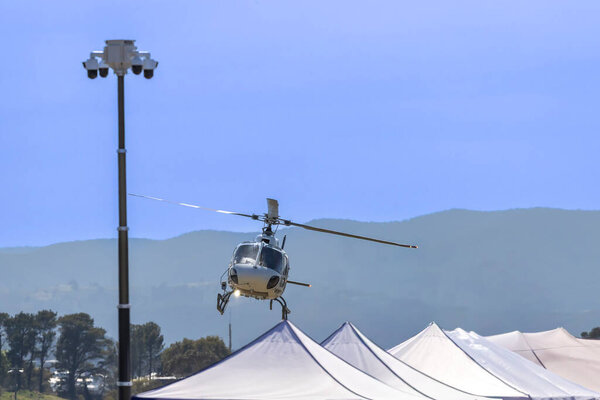Фотография туристического экскурсионного вертолета, летающего вокруг спортивного события в региональной Австралии.