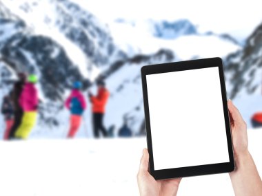 tablet in hands and people skiing in the background clipart