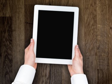 bir tablet ahşap bir masa üstü arka plan üzerinde tutan kadının el