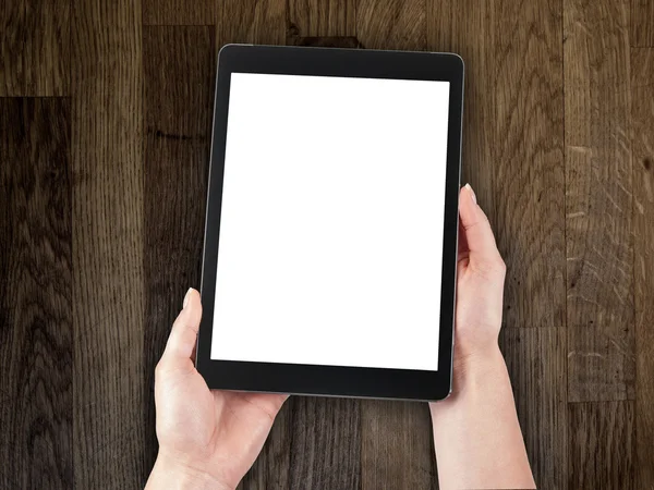 Woman's hand holding a tablet on the background of a wooden tabletop — Stock Photo, Image