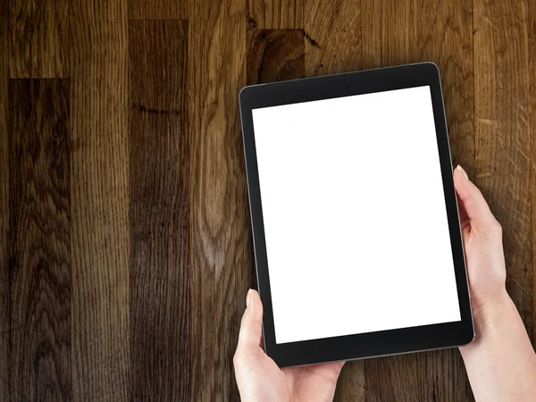 Woman's hand holding a tablet on the background of a wooden tabletop — Stock Photo, Image