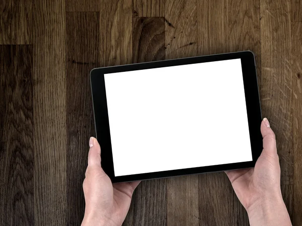 Mão da mulher segurando um tablet no fundo de uma mesa de madeira — Fotografia de Stock