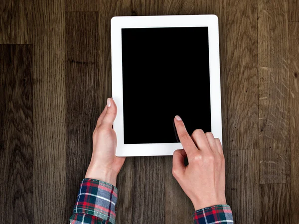 Kvinnans hand som håller en tablett på bakgrund av en trä bordsskiva — Stockfoto