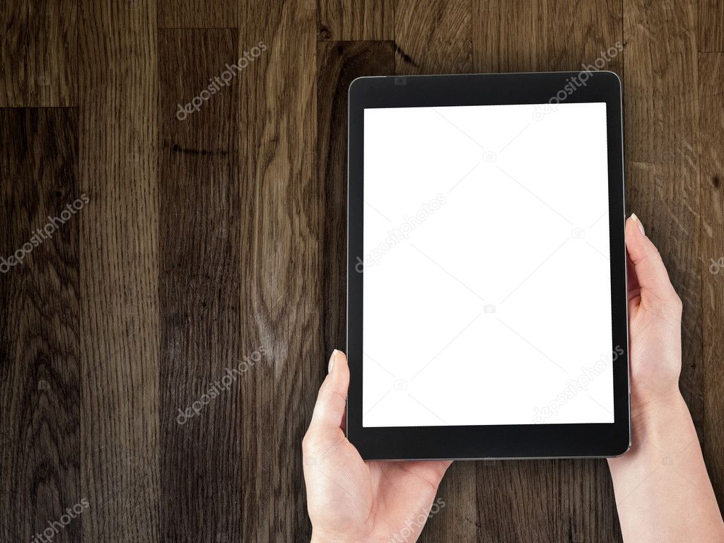 woman's hand holding a tablet on the background of a wooden tabletop