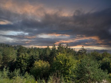 Yeşil ormanın üzerindeki dağlarda dramatik bir gökyüzü