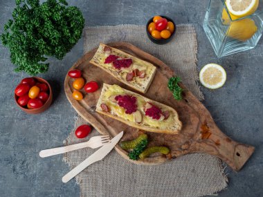 Tahtada peynirli güveç ve sosis, yanında renkli şampanya domatesleri.