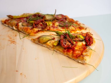 Son iki dilim vejetaryen pizzası, ahşap bir masada, arka planda.