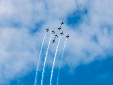 Normandiya, Arromanches 8 Haziran 2024.Bir grup akrobatik uçak mavi gökyüzünde bir hava gösterisi düzenleyerek kırmızı, beyaz ve mavi renkli duman bulutları yarattı. Dinamik sahne hassasiyeti gösterir. 