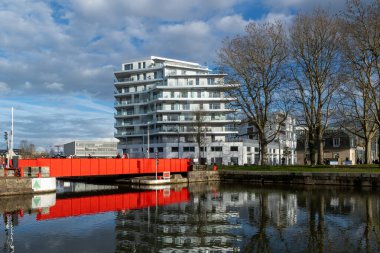 Modern binaların suya yansıdığı bir kanalda kırmızı şehir köprüsü..