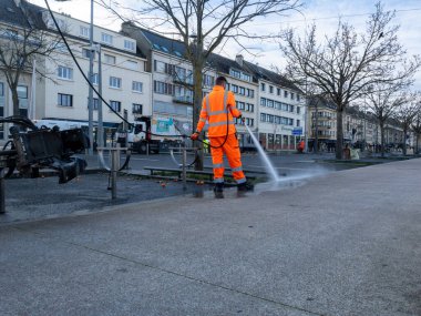Belediye çalışanı, belediye sağlık hizmetleri kapsamında su jeti ile kaldırımı temizliyor. Kentsel temizlik ve kamusal alan bakımı.
