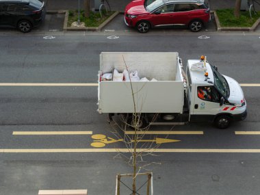 Beyaz belediye servis kamyonu işaretli bisiklet şeridiyle şehir yolunda gidiyor. Şehir bakımı ve kamu altyapı kavramı.