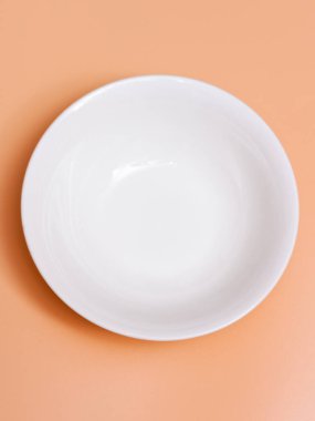 Turuncu arka planda büyük seramik beyaz bir kase. Üst görünüm.