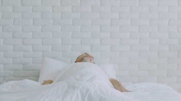 Літній Азіатський Чоловік Розтягує Руку Після Пробудження Ліжку Дивиться Вікнами — стокове відео