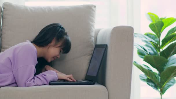可爱的女孩在沙发上使用电脑笔记本电脑 在网上学习 在客厅与朋友见面 — 图库视频影像
