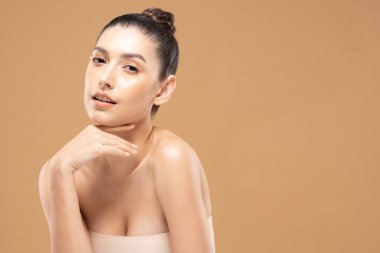 Güzel Cazibeli kadın çene gülümsemesine dokunuyor temiz ve taze tenli mutlu ve neşeli, olumlu duygusal, bej arka planda soyutlanmış, güzellik kozmetiği ve kaplıca tedavisi kavramı