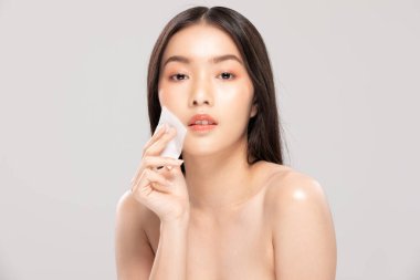 Çekici, çekici, Asyalı genç kadın gülümseyecek ve makyaj malzemesi ile doku kullanacak. Temiz ve sağlıklı cilt, beyaz arka plan, güzellik kozmetik konsepti.