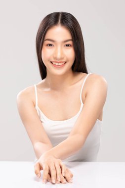 Güzel Asyalı kadın kameraya bakıyor temiz ve taze tenli gülümsüyor mutluluk ve neşe olumlu duygusal, beyaz arka planda izole edilmiş güzellik ve kozmetik kavramı