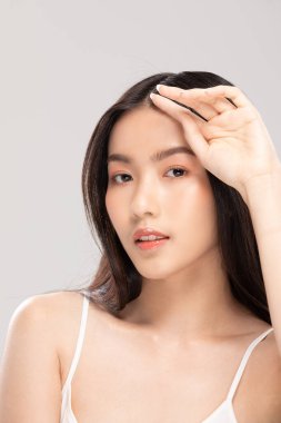 Güzel Asyalı kadın kameraya bakıyor temiz ve taze tenli gülümsüyor mutluluk ve neşe olumlu duygusal, beyaz arka planda izole edilmiş güzellik ve kozmetik kavramı