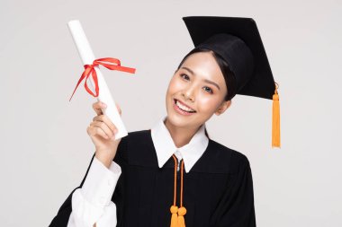 Güzel, Çekici Asyalı kadın, elinde sertifikası, gururu ve mutluluğu ile beyaz arka planda izole edilmiş, Eğitim Başarı Konsepti ile kep ve cübbe gülümsemesiyle mezun oldu.