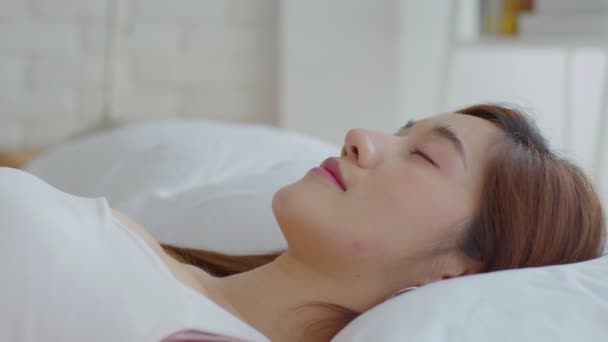 顔を閉じてアジアの若い女性閉じる彼女の目はベッドの上に横たわって 居心地の良いベッドルームで快適で幸せ ヘルスケアコンセプト — ストック動画
