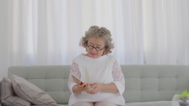 亚洲老年妇女洁白的白发头疼偏头痛和偏头痛在家沙发上的疼痛和疾病 老年人护理理念 — 图库视频影像