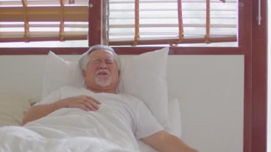 Asya 'lı yaşlı bir adamın acil kalp krizi geçirmesi dolayısıyla sadece yatakta bulunan diyabet semptomlarıyla göğsüne ve hastalığına tutunması ve acil yardıma ihtiyacı olması, yaşlıların bakım konsepti.