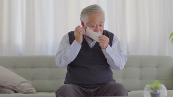 快乐的亚洲老人或老年人 戴着医疗面罩 以防止大拇指出现 可以坐在舒适的客厅沙发上 新的正常的老年人生活方式呆在家里 — 图库视频影像