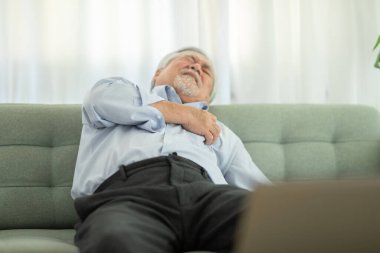 Asyalı yaşlı bir adamın acil kalp krizi geçirmesi göğüs ağrısı ve diyabet semptomları tek başına kanepede ve evde acil yardıma ihtiyacı var, yaşlılar konsepti