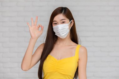 Korunaklı yüz maskesi takan Asyalı genç bir kadın koluna koronavirüs aşısı vurulduktan sonra iyi bir işaret, virüs salgını nedeniyle anti-virüs aşısı olan kendinden emin bir kadın mutluluğu.