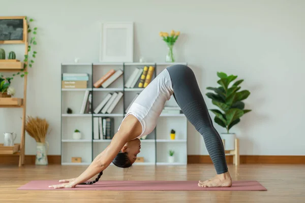 Calm of Beautiful Attractive Asian woman practice yoga Downward Facing dog or yoga Adho Mukha Svanasana pose to meditation with yoga in bedroom,Recreation in holidays concept