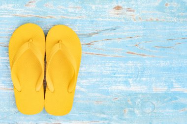 top view of yellow slippers on blue wooden background,Flat lay of summer vacation and travel concept
