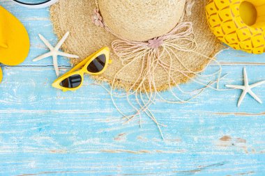 top view of yellow slippers  summer hat and sunglasses on blue wooden background,Flat lay of summer and travel equipment with copy space,Summer vacation and travel concept